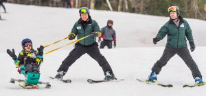 people skiing with adaptive equipment